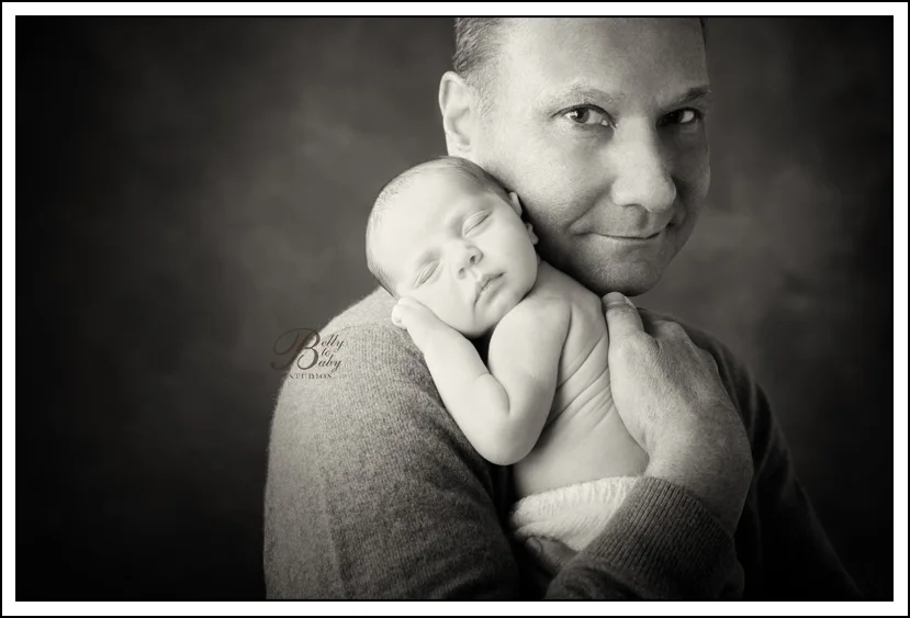 Houston Maternity Photographer Father cuddling his newborn baby during a professional newborn portrait session in Houston.