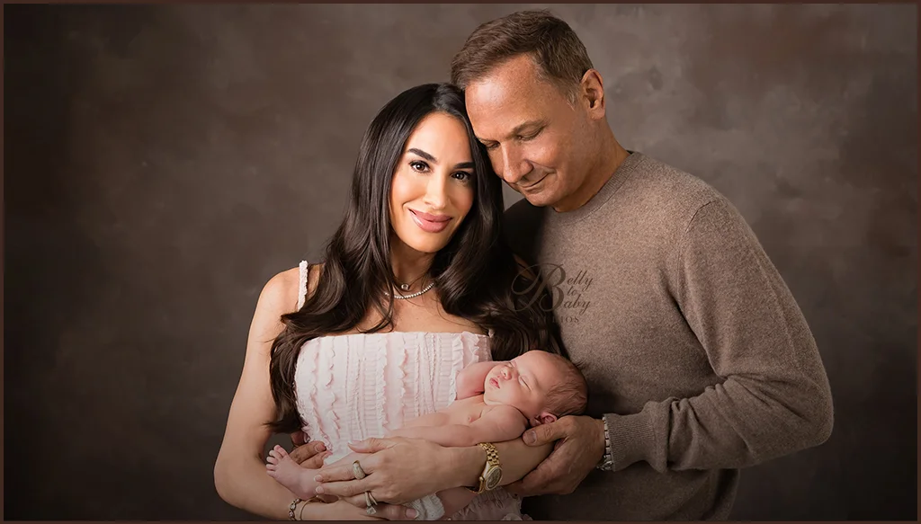Parents holding their newborn baby together during a studio family portrait Parents holding their newborn baby together during a studio family portrait
