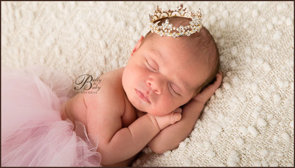 Sleeping newborn girl in a pink tutu and floral headband on a cream textured blanket Sleeping newborn girl in a pink tutu and floral headband on a cream textured blanket