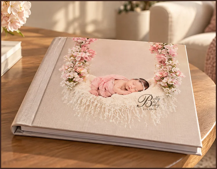 Newborn photo album featuring a sleeping baby portrait on the cover, displayed upright on a nursery shelf with neutral decor. Newborn photo album featuring a sleeping baby portrait on the cover, displayed upright on a nursery shelf with neutral decor.